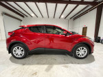 2020 Toyota C-HR LE in red, parked indoors, showcasing its sleek design and modern features.