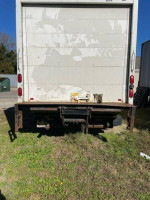 Rear view of a 2010 Mitsubishi Fuso box truck with lift gate and E-track in grassy area.