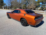 2011 Dodge Challenger in bright orange with customized look, parked on street, showcasing its sleek design.
