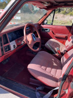 Interior of a classic Jeep Wagoneer with burgundy trim, featuring well-maintained seats and dashboard.