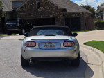 Rear view of a silver 2006 Mazda MX5 Miata parked near a home, showcasing its sporty design.