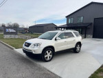 2010 GMC Acadia SLT in pearl white, featuring leather interior and modern amenities, parked outside a building.