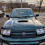 Front view of a 2015 Toyota 4Runner in green color, showcasing its distinctive hood scoop.