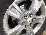 Close-up of a 2011 GMC Acadia wheel showing silver alloy rim and brake details.