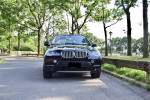 Front view of a 2013 BMW X5 xDrive35i in a park, showcasing its luxury and sporty design.