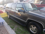 1999 Chevrolet Suburban parked on grass, showcasing its sleek exterior and new tires.