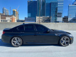 2014 BMW M5 in black parked on rooftop with city skyline background, showcasing luxury and elegance.