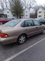 Side view of a 1998 Toyota Avalon XLS FWD parked in a residential area with some rust spots.