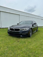 2017 BMW 540i Xdrive M Sport parked on grass, showcasing its sleek design and premium features.