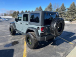 2014 Jeep Wrangler in Anvil gray with lifted suspension and off-road tires parked in a scenic area.