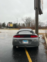 Gray 1995 Mitsubishi Eclipse GST parked, showcasing its modified rear and performance exhaust system.