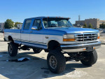 1995 Ford F350 Quad Cab 4WD with monster lift and new tires, showcasing powerful design and off-road capabilities