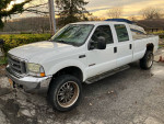 2004 Ford F350 diesel truck with 145,000 miles, showing rust and unique wheel rims, parked outdoors.