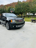 2010 GMC Sierra Denali 1500 AWD in front of a house, showcasing a black exterior and stylish design.