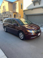2014 Honda Odyssey in maroon color parked on the street, showcasing its luxury features and excellent condition.