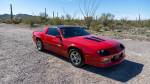 Red 1988 Chevy Camaro IROC parked on a gravel road, showcasing classic design with recent updates.