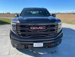 Front view of a 2022 GMC Sierra 1500 AT4X in black with a clear blue sky background.