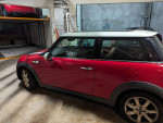 Red Mini Cooper parked, showcasing its premium features and great condition with new tires and headlights.