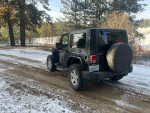 2009 Jeep Wrangler Rubicon parked in snowy terrain, showcasing its rugged design and capabilities.