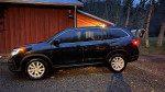 2019 Honda Pilot in dark green, parked near a wooden cabin, showcasing clean exterior and fresh tires.