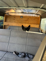Interior of a 1997 Dodge 3500 passenger van showcasing seats and a dog peeking out.
