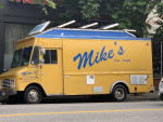 1997 Chevy P30 food truck painted yellow with blue lettering, parked in a street setting, showcasing its catering features.