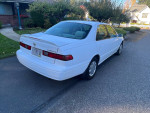 1999 Toyota Camry CE in white, showing rear and side view, well-maintained with low mileage.