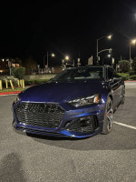 2021 Audi RS 5 Sportback in blue parked at night, featuring a sleek design and modern headlights.