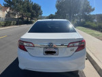 Rear view of a 2013 Toyota Camry XLE FWD in excellent condition on a sunny street.