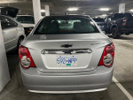 Rear view of a 2015 Chevrolet Sonic LT parked indoors, showcasing its clean appearance and license plate.