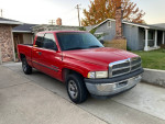 Red 1998 Dodge Ram 1500 V8 truck parked in front of a house, featuring low mileage and a tow hitch.