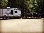 2012 Ford F350 Super Duty with black leather interior parked beside a recreational trailer in natural surroundings.