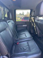 Interior view of a 2012 Ford F350 Super Duty with black leather seats, showcasing spacious rear seating.