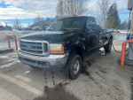 1999 Ford F-350 Super Duty pickup truck at a gas station with doors open, for sale at $2,600 cash.