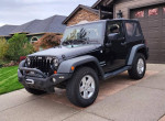 2011 Jeep Wrangler Sport 4WD parked on a driveway, showcasing new LED headlights and a rugged design.
