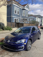 2019 Volkswagen e-Golf in Atlantic Blue parked on the street, showcasing its modern design and low mileage.