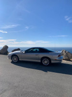 2002 Chevrolet Camaro SS parked near rocks with a scenic view, showcasing T-top and aftermarket enhancements.