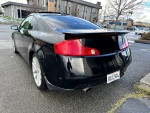 2005 Infiniti G35 Coupe in black with aftermarket rims and exhaust, parked on a street.