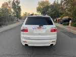 Rear view of a white 2011 GMC Acadia Denali with 135K miles parked on a residential street.