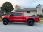 2019 Toyota Tacoma TRD Off Road 4WD in red, showcasing new tires and upgrades, parked outside a house.