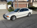 2000 BMW 540i in Alpine white, featuring beige leather interior, parked in a residential area.
