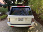 2012 Land Rover Range Rover Supercharged rear view in a garden, showcasing its white color and elegant design.