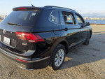 2018 Volkswagen Tiguan in black, showcasing clean exterior and stylish design near water.