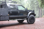 California legal 2000 F550 4x4 truck with 41” tires parked in a forested area, showcasing upgraded features.