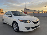 2010 Acura TSX in White Pearl color parked with a cityscape backdrop, showcasing its sleek design and excellent condition.