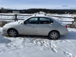 2002 Hyundai Elantra parked in snow, featuring new tires and manual transmission, with minor windshield crack.
