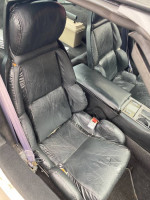 Interior view of a 1990 Chevrolet Corvette with black leather seats, showcasing the driver's seat and console.