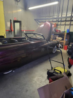 1965 Ford Mustang convertible in garage with hood raised and tools nearby, showcasing car collection.