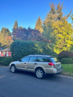 2008 gold Subaru Outback 2.5 XT Limited AWD parked on a residential street surrounded by greenery.