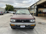 Front view of a 1999 Nissan Pathfinder XE RWD in a parking lot, showcasing its clean design and 52,000 miles.